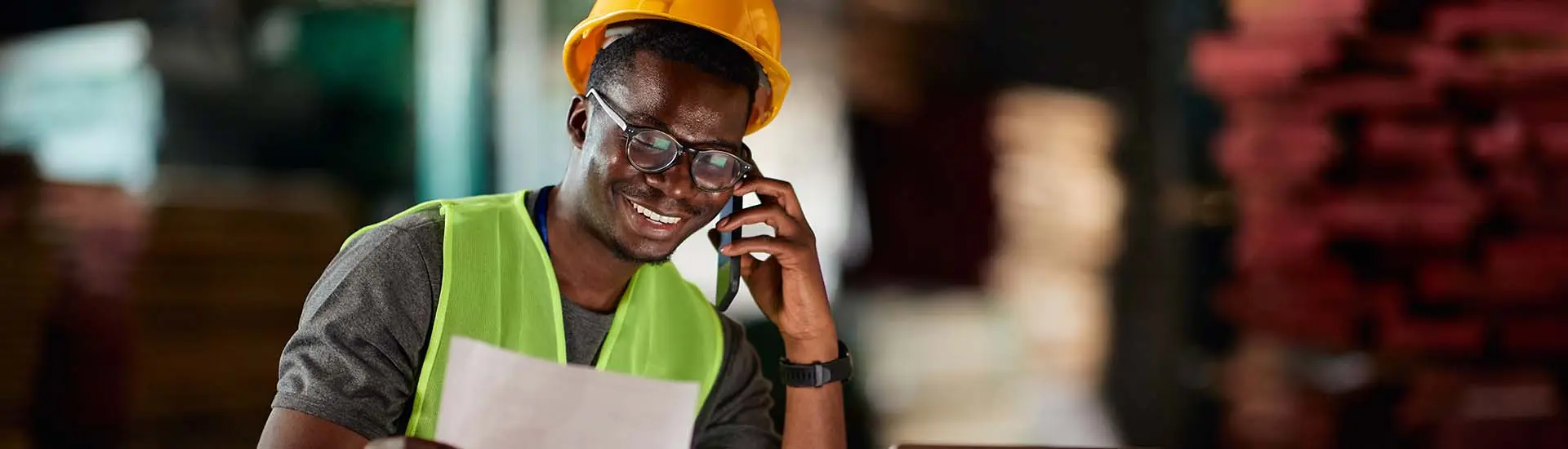 worker wearing high visibility vest and hard hat speaking on a phone
